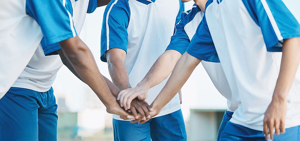 Lagkamrater som såtr i en cirkel och har lagt varandras händer omlott som för att ladda inför en match.